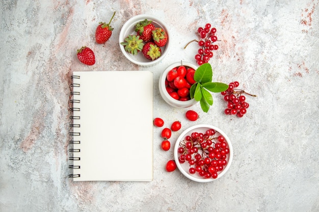 흰색 테이블에 메모장이 있는 상위 뷰 신선한 붉은 열매 붉은 과일 베리 신선한