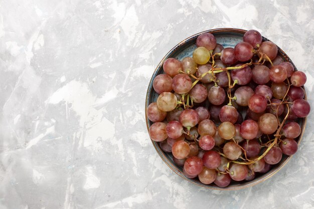 Вид сверху свежий красный виноград сочные спелые сладкие фрукты на белом столе