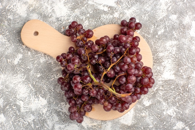 Vista dall'alto uva rossa fresca frutta pastosa e succosa su superficie bianco chiaro