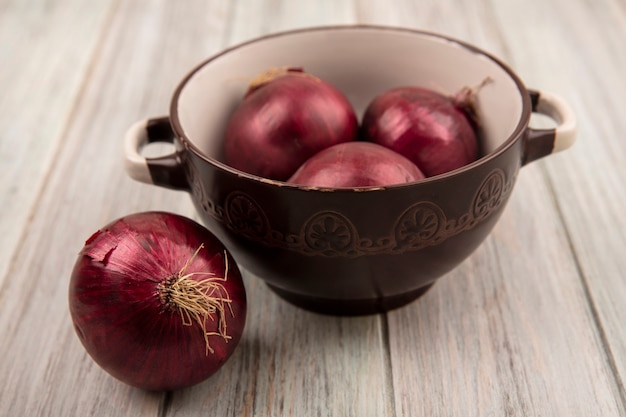 Free photo top view of fresh red onions on a bowl on a grey wooden surface