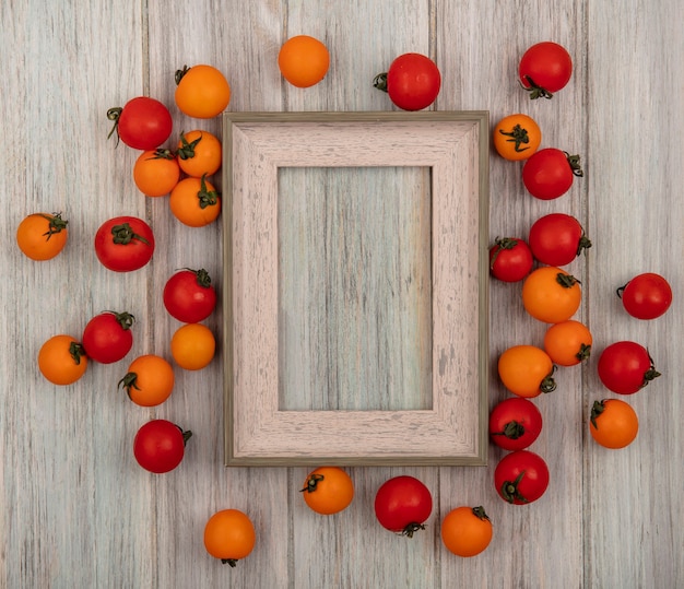 Top view of fresh red and orange tomatoes isolated on a grey wooden background with copy space