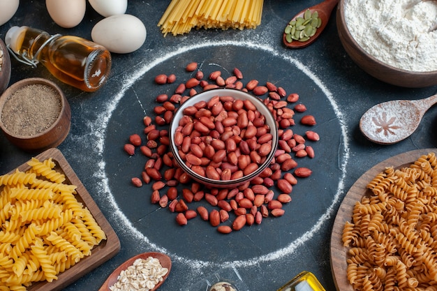 Top view fresh red peanuts with raw pasta seasonings and eggs on dark table color food meal nut snack egg milk dough