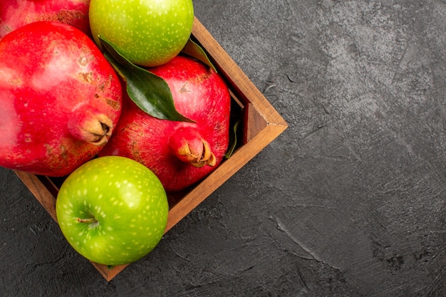 Foto gratuita vista dall'alto melograni rossi freschi con mele verdi sul colore della frutta matura superficie scura