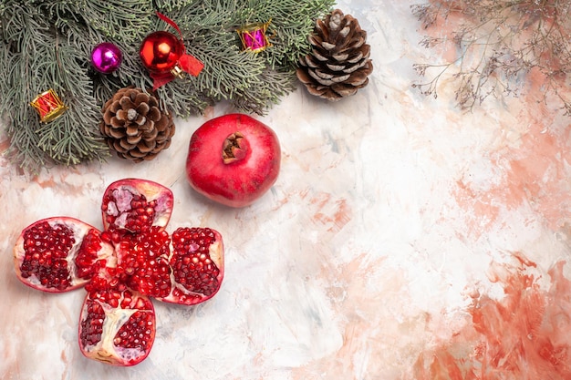 Top view fresh red pomegranates with tree and toys on light background