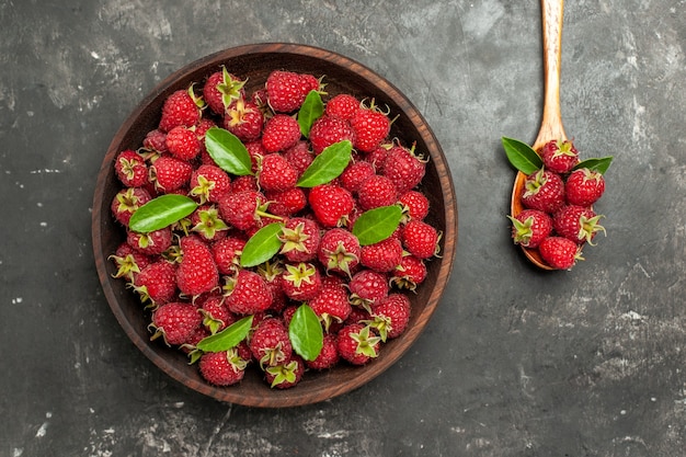 Top view fresh red raspberries inside brown plate on grey background