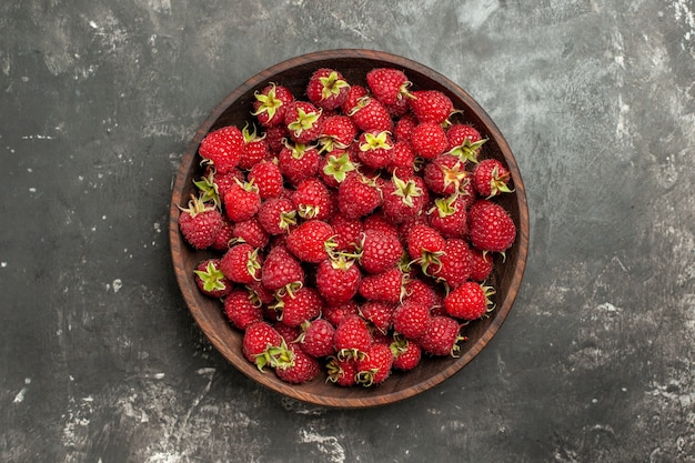 회색 배경에 있는 접시 안에 있는 신선한 빨간 나무 딸기