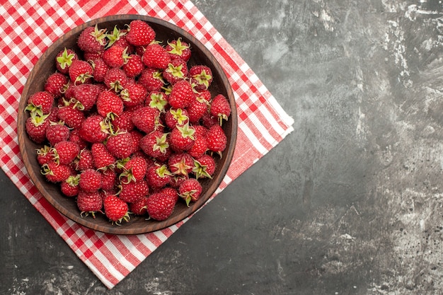 회색 배경에 있는 접시 안에 있는 신선한 빨간 나무 딸기