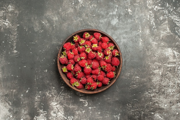 Top view fresh red raspberries inside plate on grey background