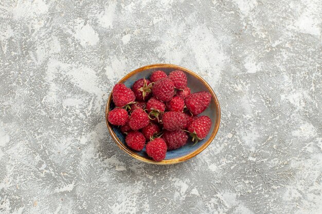 Top view fresh red raspberries inside plate on white background