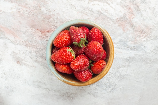 Вид сверху свежей красной клубники внутри маленькой тарелки на белом столе ягодные фрукты дикие