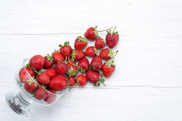 Top view of fresh red strawberries inside and outside plate on white, fruit berry fresh mellow