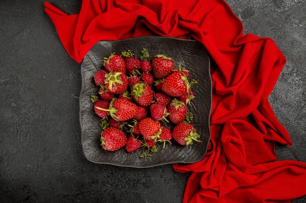 Vista dall'alto fragole rosse fresche all'interno del piatto sulla bacca di frutta pavimento scuro