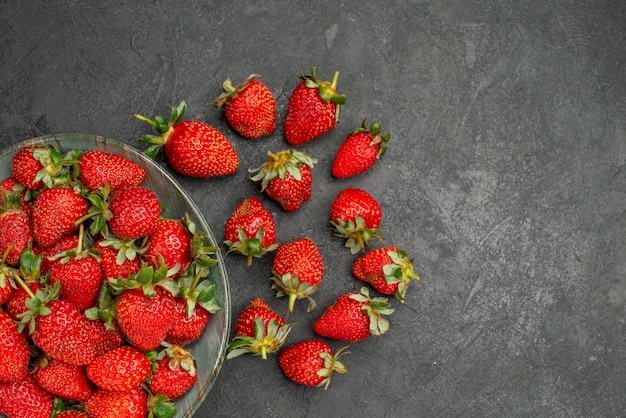 Top view fresh red strawberries inside plate on grey background