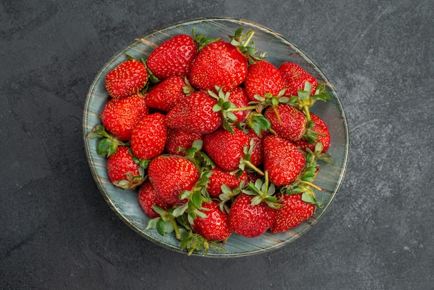 Top view fresh red strawberries inside plate on grey background