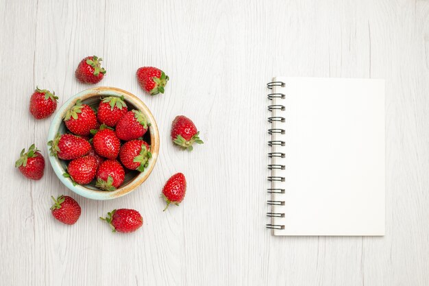 Top view fresh red strawberries inside plate on a white desk