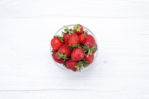 Вид сверху свежей красной клубники внутри прозрачной тарелки на светло-белом, свежем фруктовом ягоде