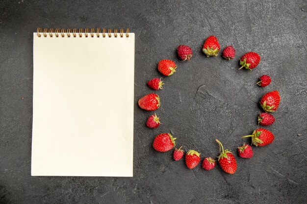 Top view fresh red strawberries lined on a dark-grey table color berry fruit