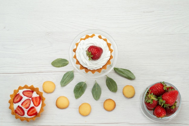 가벼운 책상에 케이크와 쿠키, 신선한 과일 베리와 함께 신선한 빨간 딸기 부드럽고 맛있는 딸기의 상위 뷰