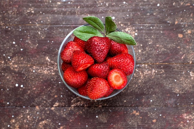 A top view fresh red strawberries mellow and juicy inside round bowl on the brown background berry fruit fresh color red