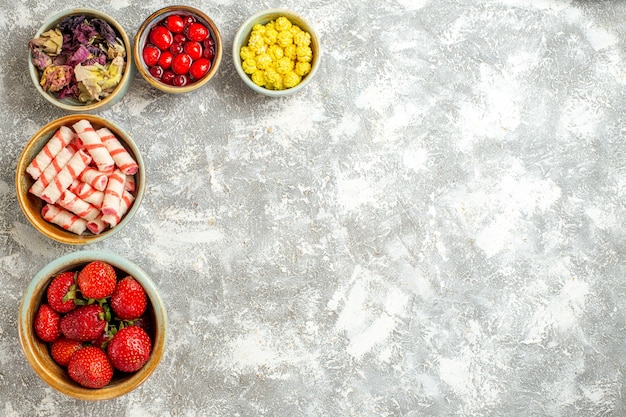 Top view fresh red strawberries with candies on white surface berry fruit red candy