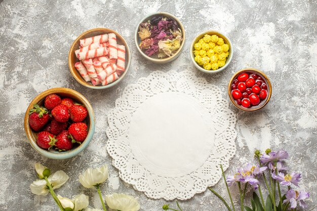 Top view fresh red strawberries with candies on white surface color berry fruit candies