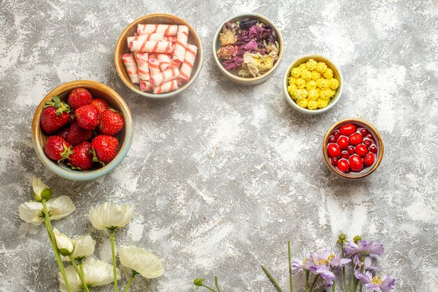 Top view fresh red strawberries with candies on white surface color berry fruits candy