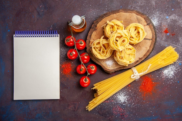 Top view fresh red tomatoes with raw italian pasta on a dark background raw salad pasta food meal