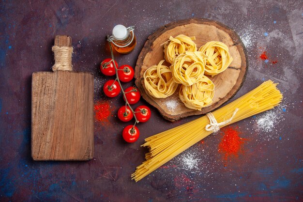 Вид сверху свежие красные помидоры с сырой итальянской пастой на темном фоне, сырой салат, паста, еда, еда