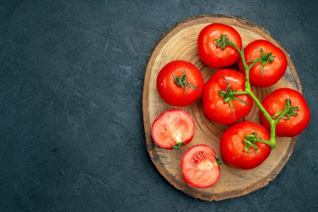 여유 공간이 있는 어두운 탁자에 있는 신선한 빨간 토마토 나무 판자