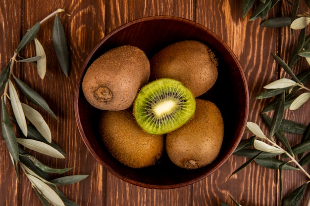 Top view of fresh ripe kiwi fruits in a wooden bowl on rustic