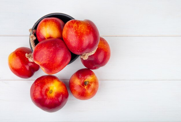 Top view of fresh ripe nectarines in a small bucket on white with copy space