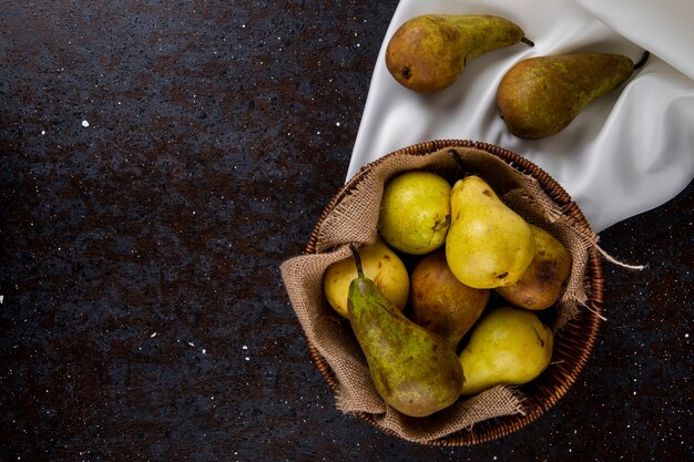 Top view of fresh ripe pears in a wicker basket on black background with copy space