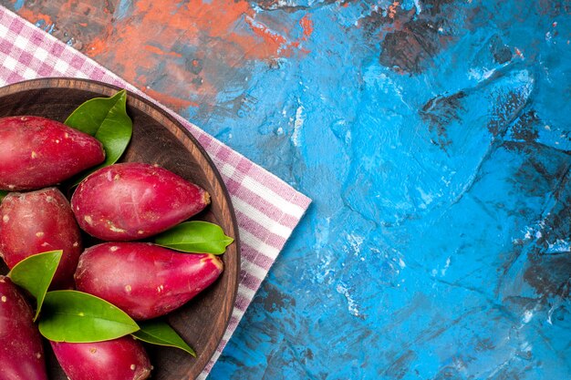 Top view fresh ripe plums inside plate on blue background