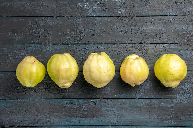 Top view fresh ripe quinces sour fruits lined on a dark-blue rustic desk plant fruit tree ripe fresh