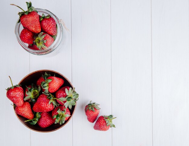 Top view of fresh ripe strawberries in a wood bowl on white with copy space