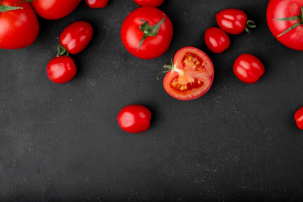 コピースペースと黒の背景に散在している新鮮な完熟トマトのトップビュー