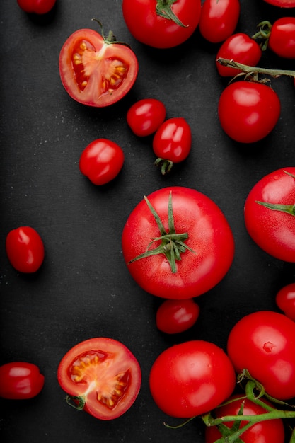 Top view of fresh ripe tomatoes scattered on black background