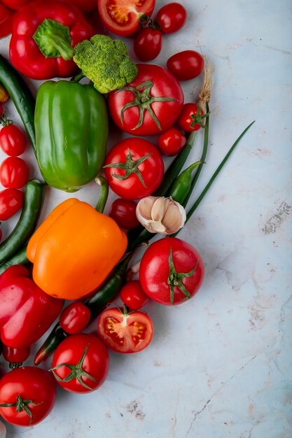 Top view of fresh ripe vegetables tomatoes green chili pepper bell pepper garlic broccoli and onion on marble background