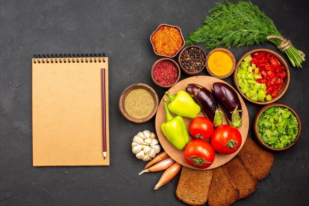 Top view fresh ripe vegetables with greens and dark bread loafs on a dark surface salad food meal health vegetable