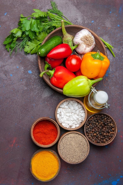 Top view fresh ripe vegetables with greens and seasonings on dark surface salad meal vegetable ripe color