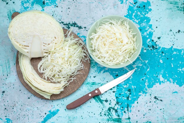 Free photo top view of fresh sliced cabbages with half whole vegetable on bright-blue desk, vegetable food meal snack healthy salad