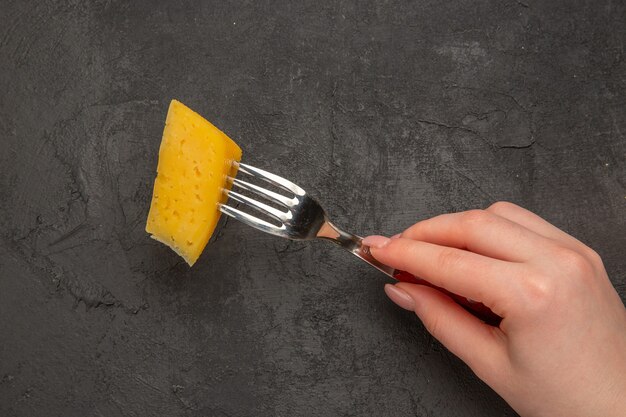 Top view fresh sliced cheese on fork dark background