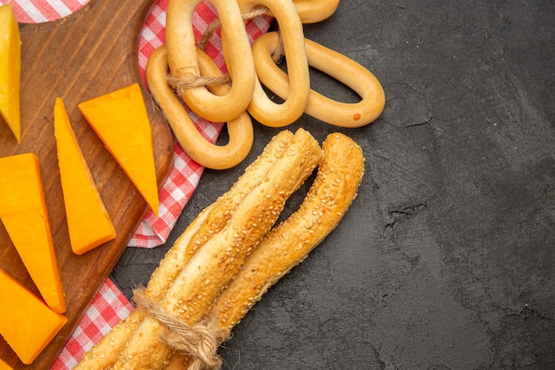 Foto gratuita formaggio fresco a fette vista dall'alto con panini e cracker su sfondo grigio scuro