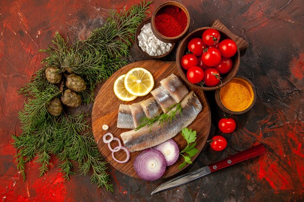 Top view fresh sliced fish with fresh tomatoes on dark background