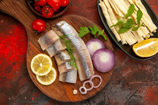 Top view fresh sliced fish with onion rings and fresh tomatoes on dark background