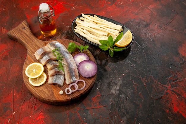 Top view fresh sliced fish with onion rings and lemon on a dark background