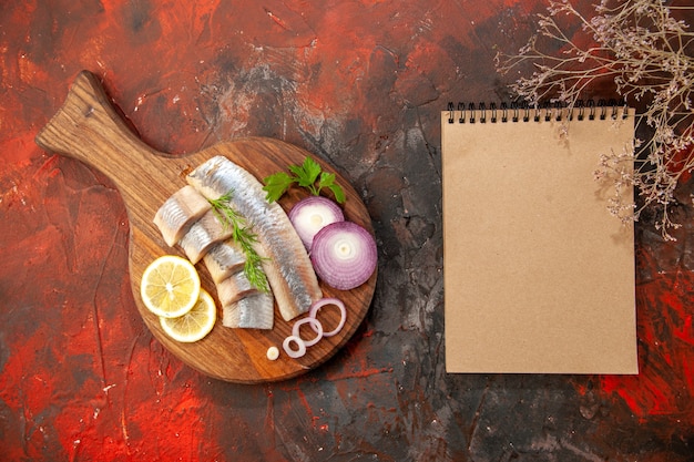 Free photo top view fresh sliced fish with onion rings and lemon on dark background