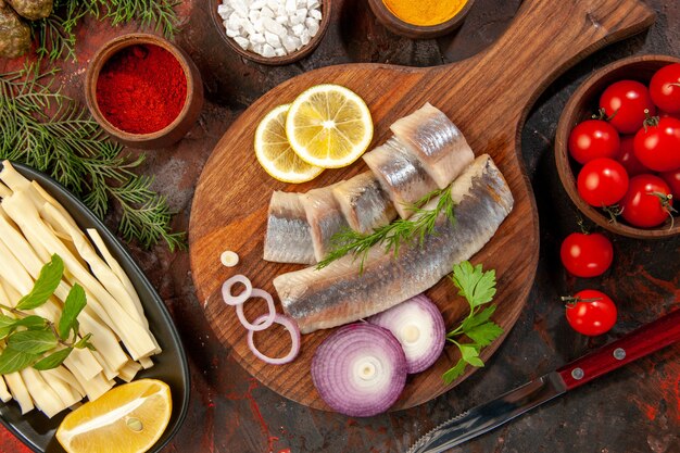 Top view fresh sliced fish with seasonings tomatoes and cheese on dark background