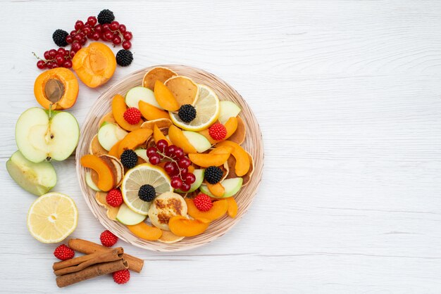 Вид сверху свежие нарезанные фрукты красочные и сочные на деревянном столе и белый фон фрукты цвет еда фото