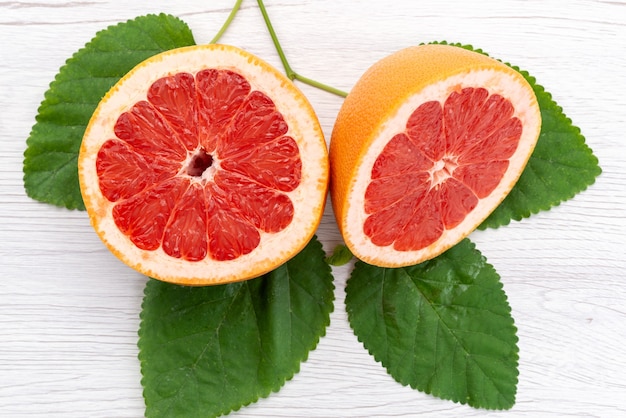 A top view fresh sliced grapefruit mellow and juicy along with green leaves on white, citrus fruit juice color